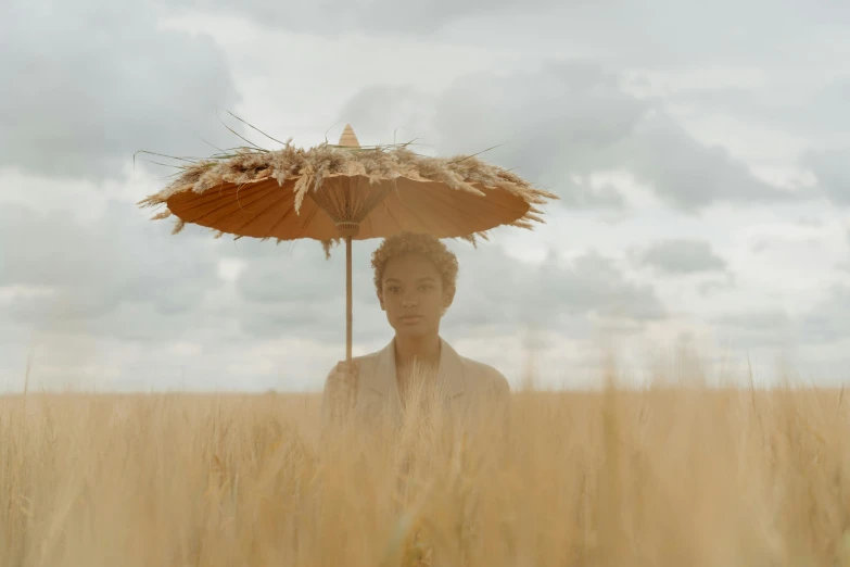 a person standing in a field with an umbrella, by Emma Andijewska, unsplash contest winner, afrofuturism, portrait of willow smith, cinema still, brown, ignant