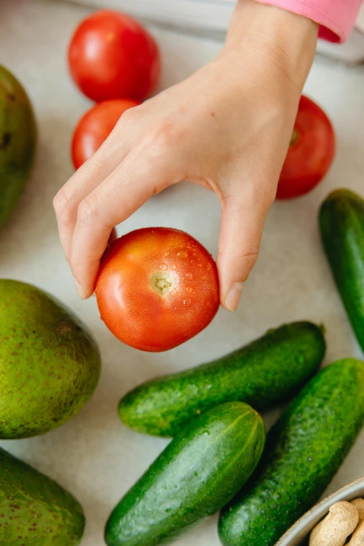 a person holding an apple surrounded by cucumbers and tomatoes, by Julia Pishtar, smooth marble surfaces, avocado, morning detail, multiple stories