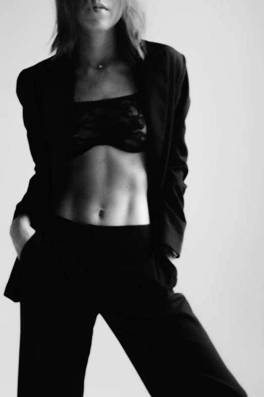 a black and white photo of a woman in a suit, a black and white photo, by Clifford Ross, unsplash, arabesque, physical : tinyest midriff ever, skintight black clothes, bella hadid, shredded