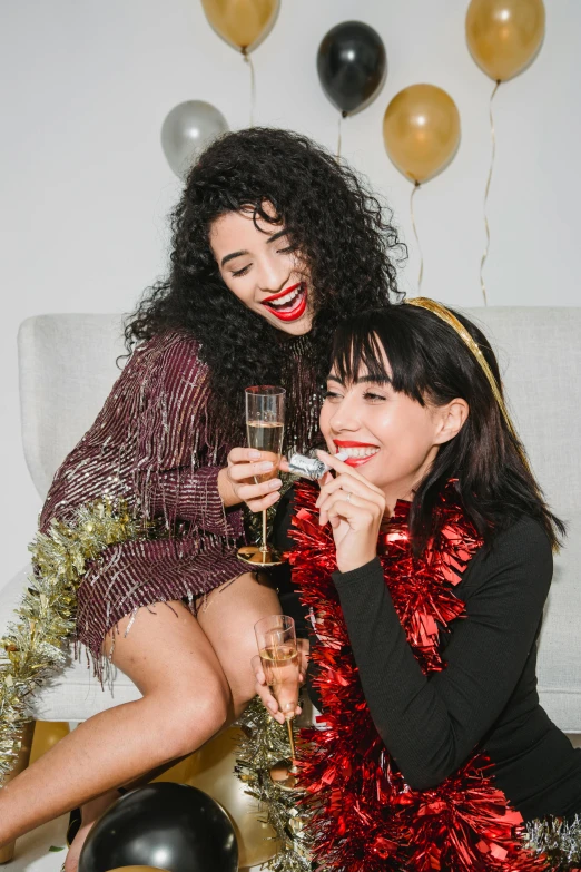 a couple of women sitting on top of a bed next to each other, trending on pexels, renaissance, new years eve, vibrent red lipstick, glittery short black hair, cheers