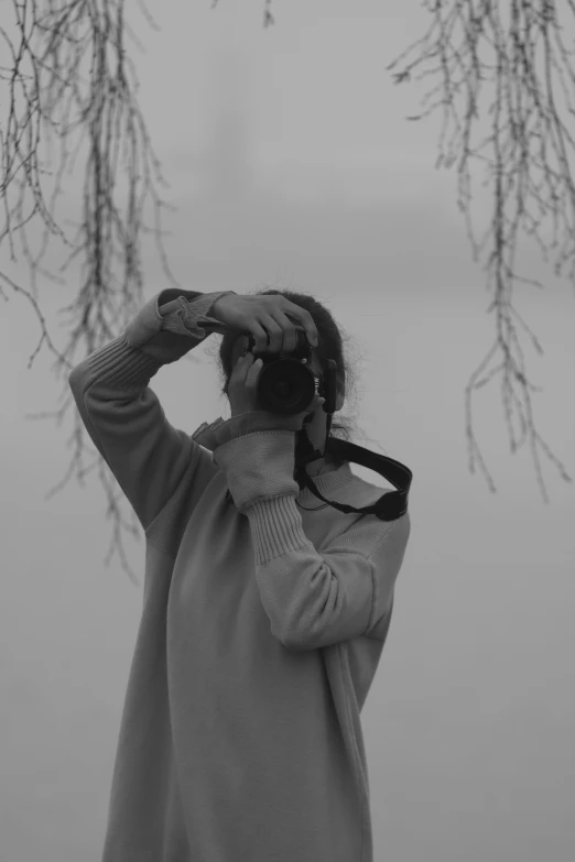 a black and white photo of a woman holding a camera, conceptual art, visor covering eyes, lakeside, ((mist)), low quality footage