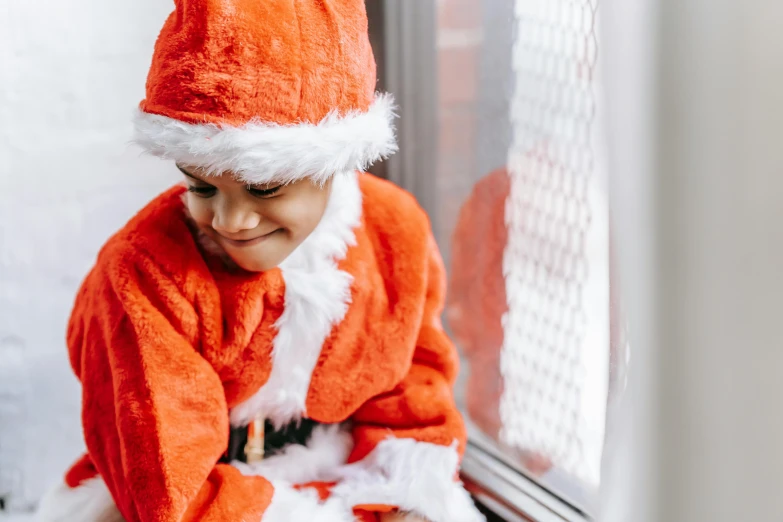 a little boy in a santa suit sitting on a window sill, pexels contest winner, hurufiyya, avatar image, profile image, orange robe, profile picture