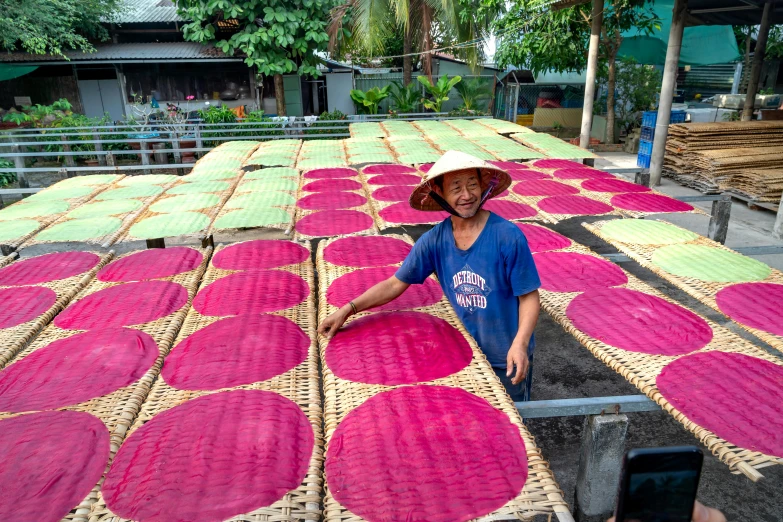 a man that is standing in front of a table, a silk screen, rice paddies, covered with pink marzipan, in style of lam manh, fish seafood markets