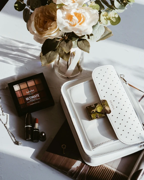 a bouquet of flowers sitting on top of a table, full makup, holding a leather purse, maybelline, browns and whites