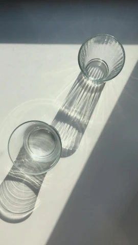 a couple of glasses sitting on top of a table, inspired by Cerith Wyn Evans, unsplash, light and space, taken on iphone 14 pro, water line surface, high angle shot, a pair of ribbed
