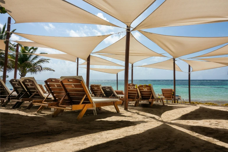 a group of lounge chairs sitting on top of a sandy beach, canopies, beautifully daylight, fan favorite, olivia de bernardinis