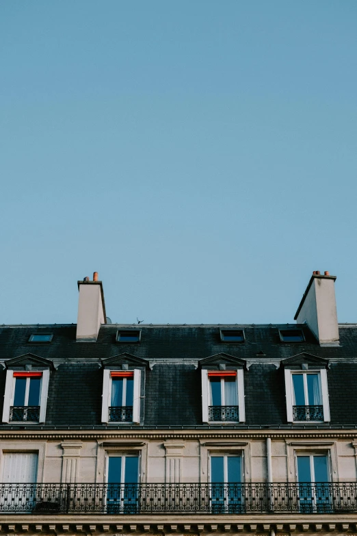 a tall building with many windows and balconies, trending on unsplash, paris school, simple gable roofs, rooftop party, trending on vsco, clear blue skies