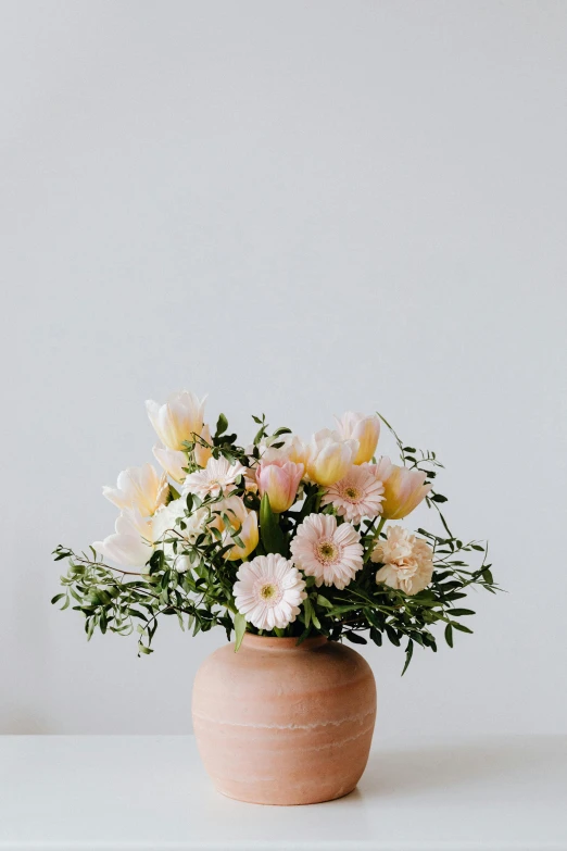 a vase filled with pink and white flowers, trending on unsplash, in shades of peach, ceramic pot, full product shot, chrysanthemum and tulips