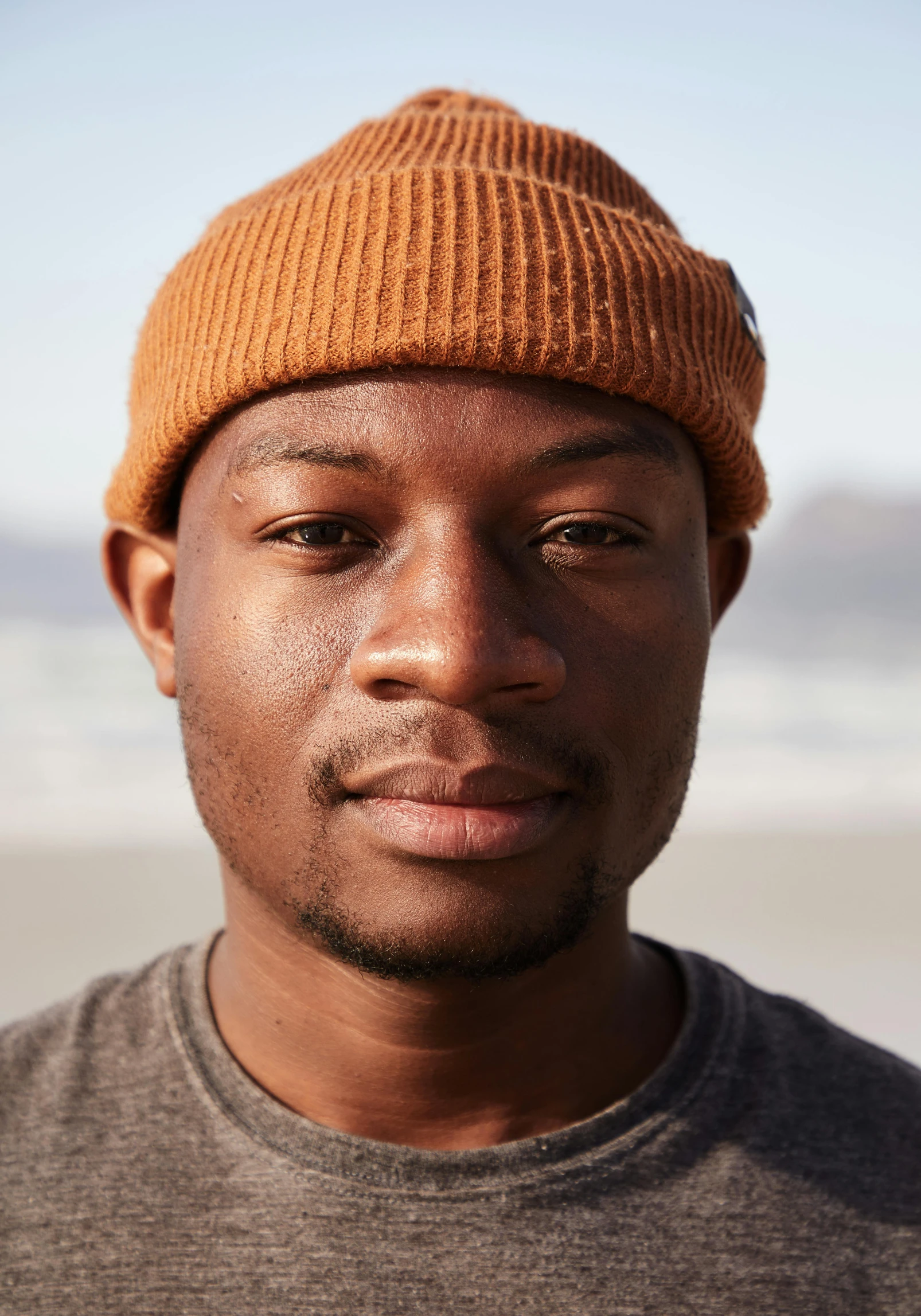 a close up of a person wearing a hat, trending on unsplash, he is wearing a brown sweater, headshot portrait, coastal, emmanuel shiru