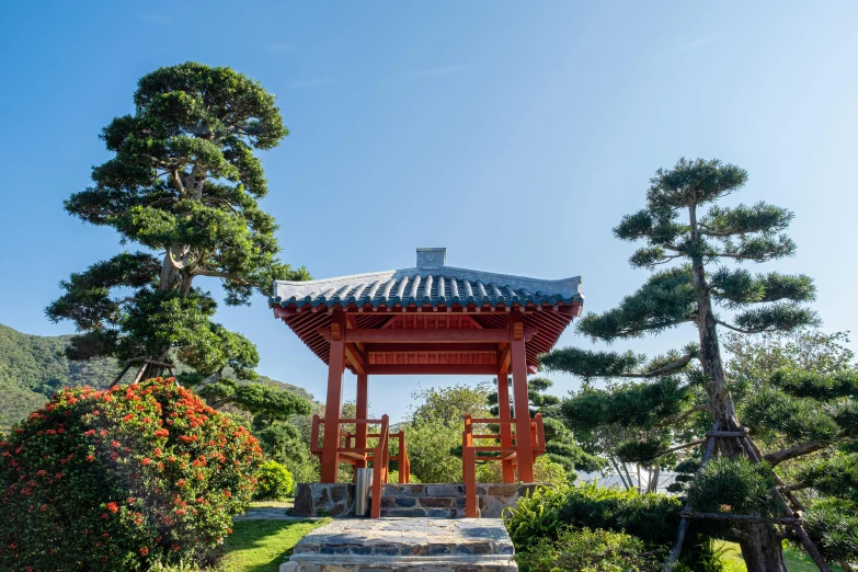 a pagoda sitting in the middle of a lush green park, inspired by Itō Jakuchū, unsplash, shin hanga, okinawa churaumi aquarium, blue sky, an archway, japanese flower arrangements