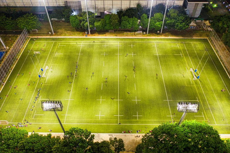 an aerial view of a soccer field at night, a tilt shift photo, by Daniel Gelon, conceptual art, sydney park, turf roof, a green, university