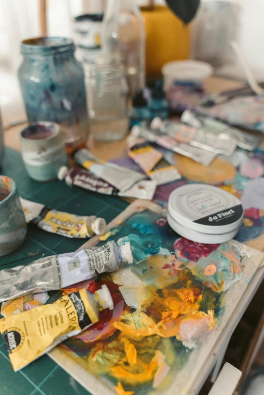 a table topped with lots of art supplies, trending on pexels, process art, liquid oilpaint, studio shot, old paints, painting on a badge