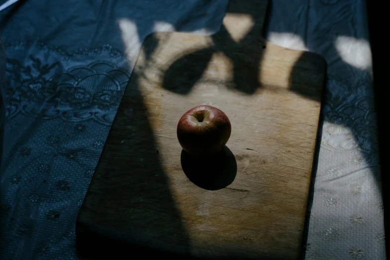 an apple sitting on top of a wooden cutting board, by Elsa Bleda, pexels contest winner, cast shadows, contre jour, background image, low iso