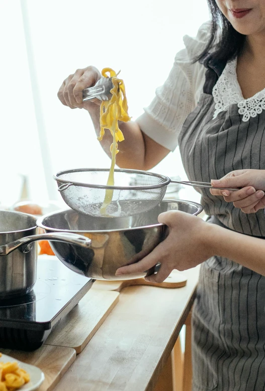 two women in aprons preparing food in a kitchen, inspired by Li Di, pexels, process art, silver and yellow color scheme, noodles, bowl filled with food, promo image