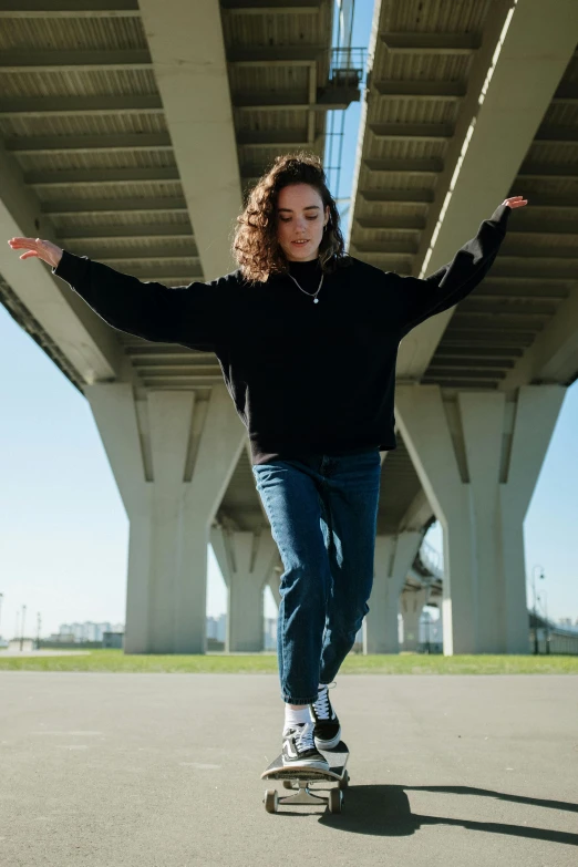 a woman riding a skateboard under a bridge, an album cover, by Grace Polit, antipodeans, wearing a black sweater, confident poses, wavy hair spread out, bay area