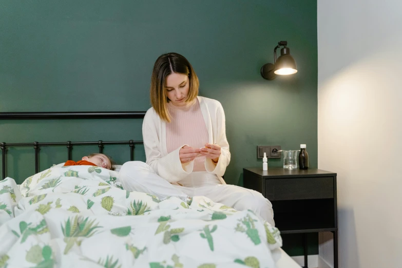 a woman sitting on top of a bed next to a baby, quack medicine, checking her phone, small and cosy student bedroom, profile image