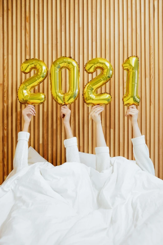 a group of people holding up balloons in the air, white robe with gold accents, 2 0 2 1, white bed, trending on markets