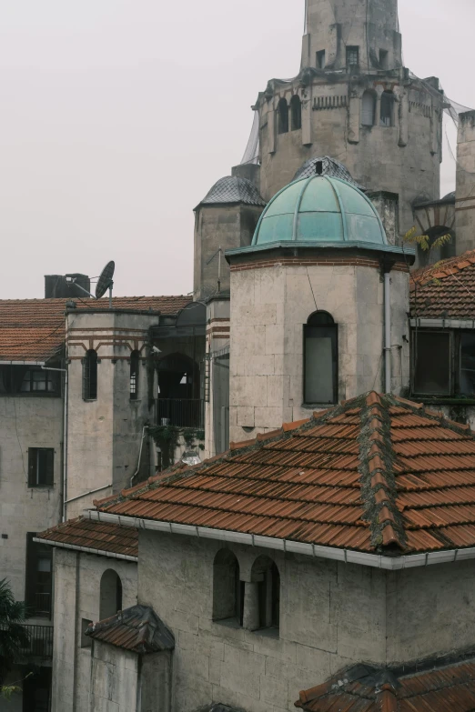 a building with a clock tower on top of it, inspired by Lajos Gulácsy, romanesque, view from the top, grey skies, an abandonded courtyard, domes