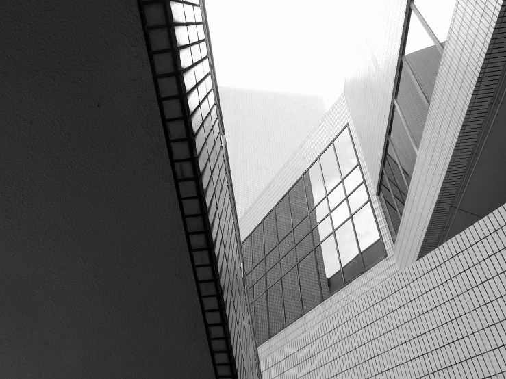 a black and white photo of a tall building, a black and white photo, inspired by Richard Wilson, light and space, angled walls, various angles, white building, complex and desaturated