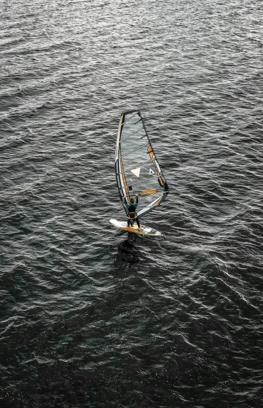 a person windsurfing in a body of water, looking down from above, body of water, in the water