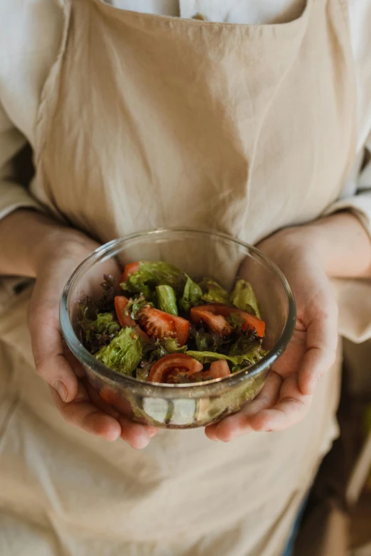 a close up of a person holding a bowl of food, abcdefghijklmnopqrstuvwxyz, salad, small, indoor picture