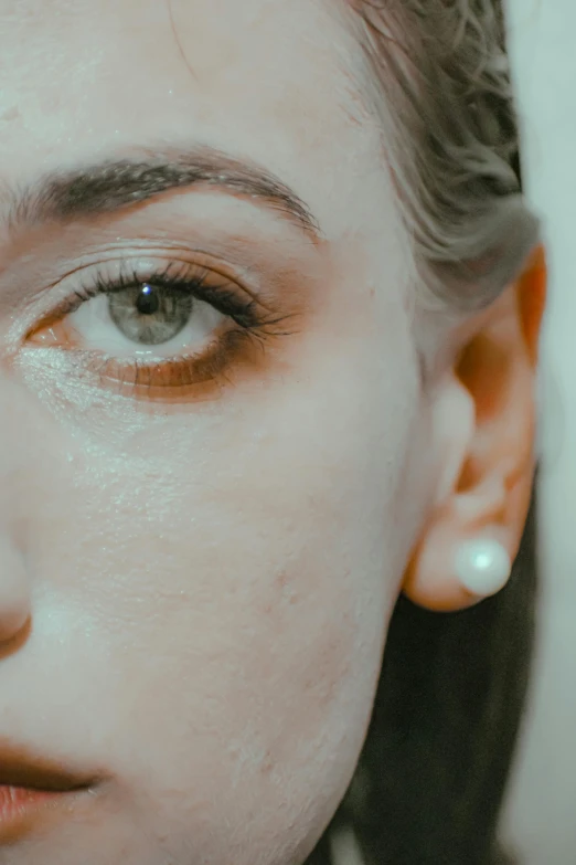 a close up of a person with makeup on, inspired by Elsa Bleda, trending on pexels, hyperrealism, wearing pearl earrings, noticeable tear on the cheek, cinematic image, eye - level medium - angle shot