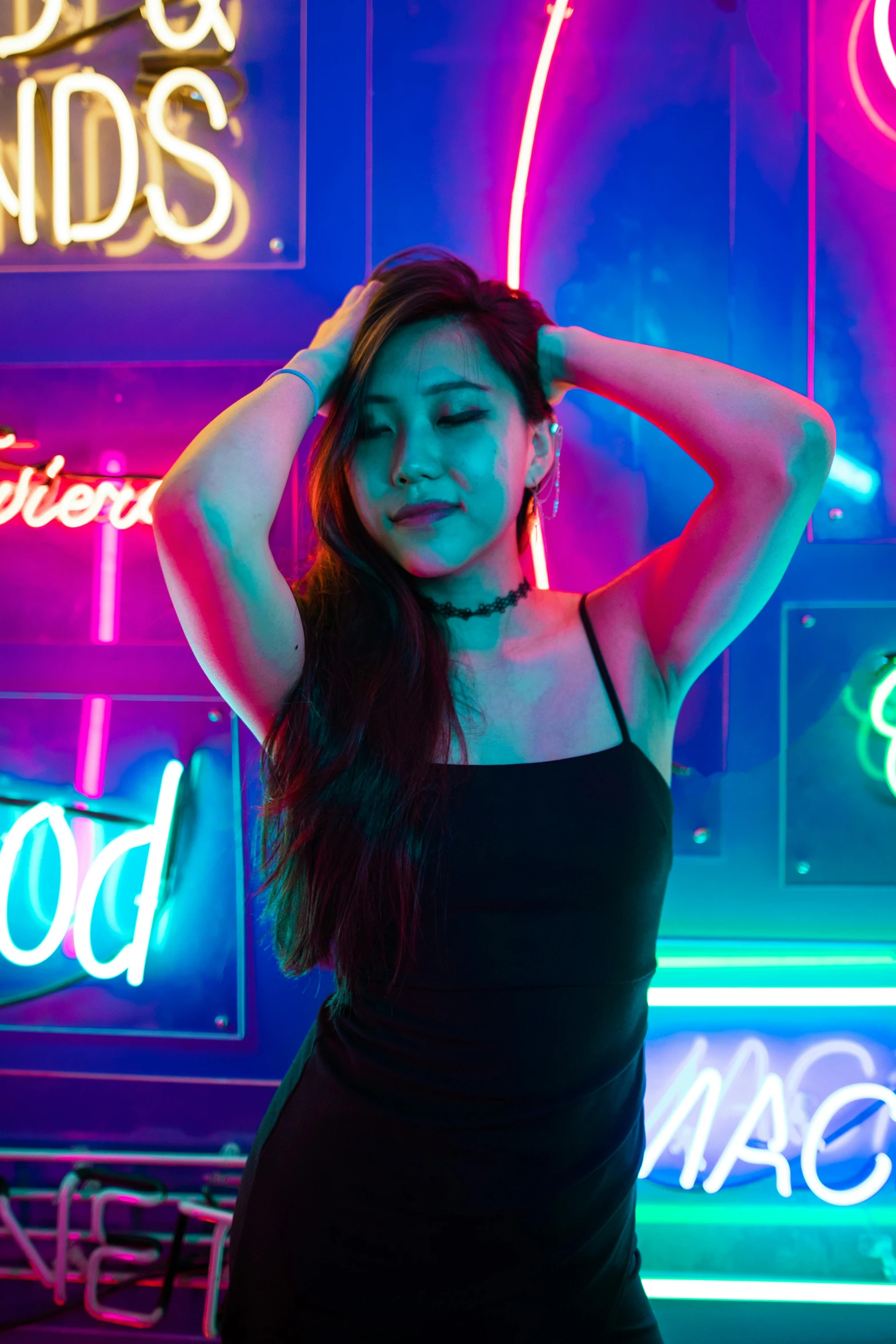 a woman in a black dress standing in front of neon signs, trending on pexels, asian girl with long hair, bright vivid color hues:1, posing for a picture, bisexual lighting