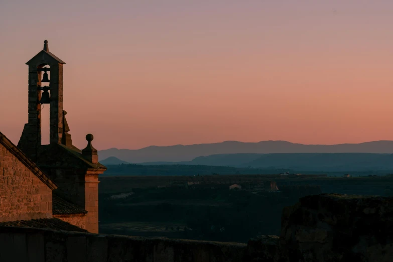 a clock tower sitting on the side of a building, a matte painting, pexels contest winner, baroque, sunset in a valley, sparse mountains on the horizon, carcassonne, pink