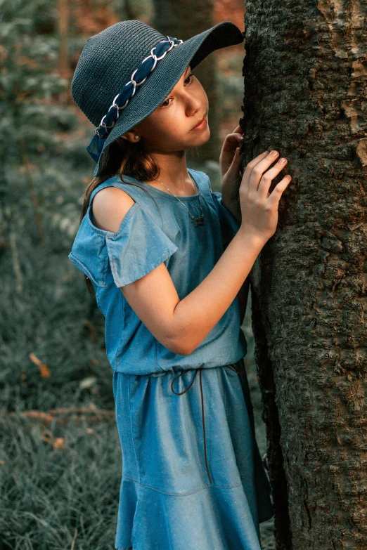 a little girl standing next to a tree, blue fedora, photo of a model, detached sleeves, wearing denim