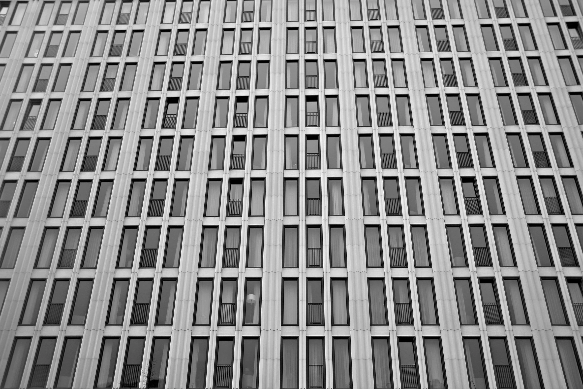 a black and white photo of a tall building, a black and white photo, inspired by David Chipperfield, unsplash, brutalism, house windows, cubicles, overwatch building, detailed grid as background