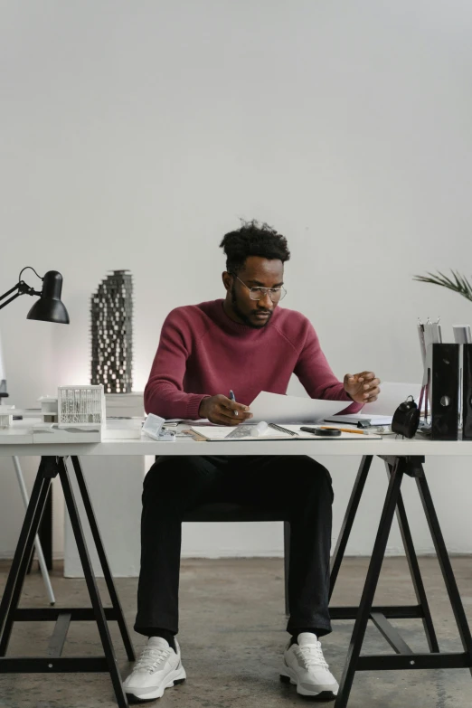 a man sitting at a desk writing on a piece of paper, inspired by Afewerk Tekle, pexels contest winner, minimalist home office, portrait of tall, african american, multi-part