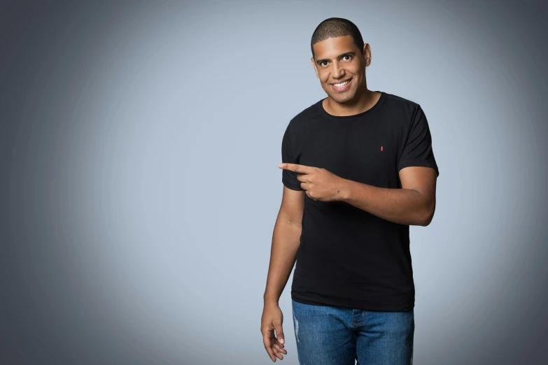 a man in a black shirt posing for a picture, inspired by Ismail Gulgee, pexels, les nabis, standup comedian, pointing, young man with medium - length, plain background