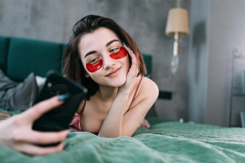 a woman laying on top of a bed holding a cell phone, a picture, trending on pexels, happening, wearing red tainted glasses, skincare, russian girlfriend, he wears an eyepatch