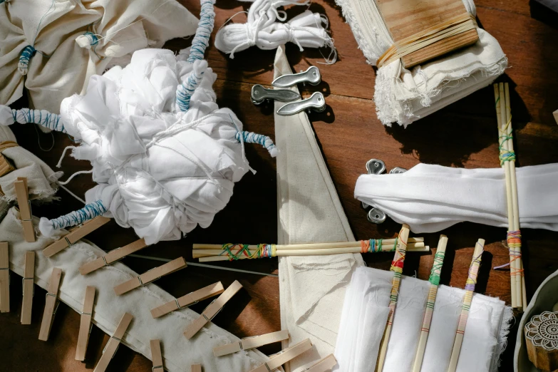 a wooden table topped with lots of white cloth, inspired by Masamitsu Ōta, unsplash, process art, pirate weapons, joints, tie-dye, intricate hakama