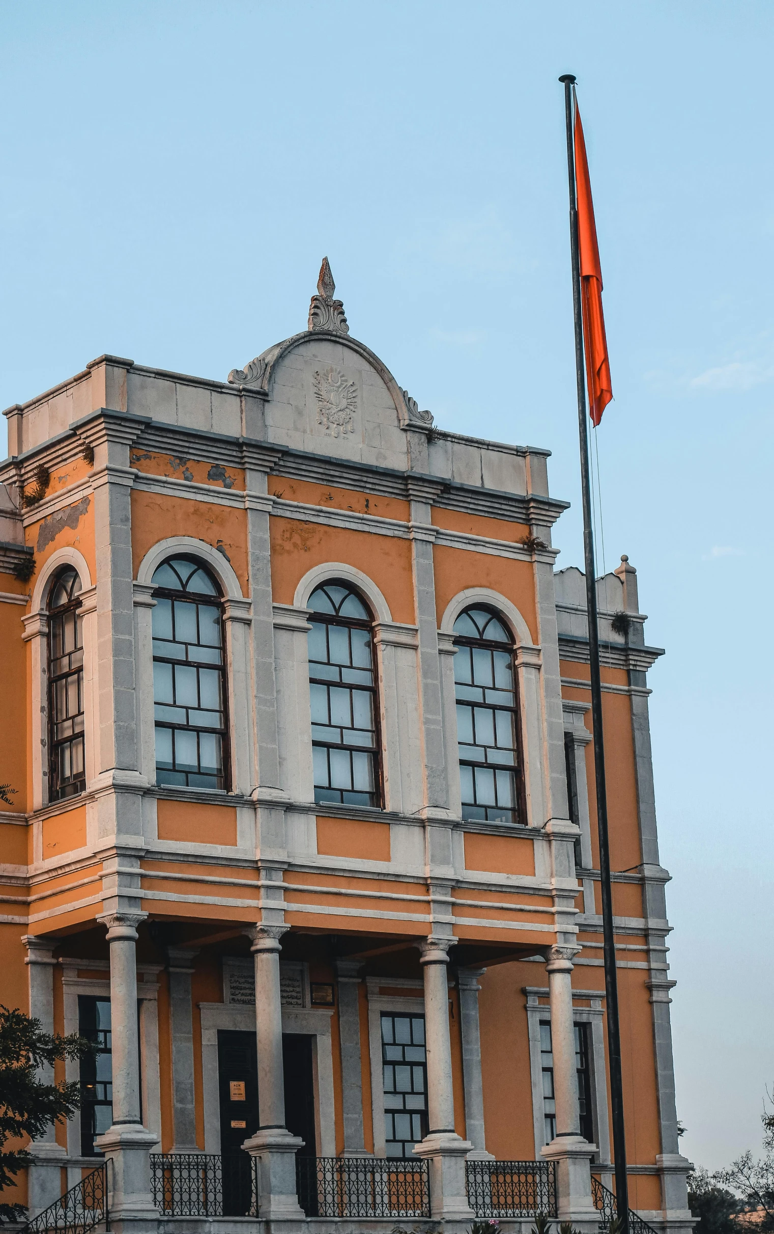 a building with a flag flying in front of it, pexels, quito school, orange details, khedival opera house, profile image, square