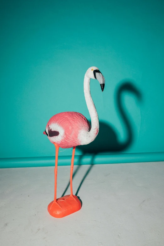 a pink flamingo standing in front of a blue wall, a surrealist sculpture, trending on unsplash, photorealism, pvc poseable, 3 d print, dimly lit, high angle