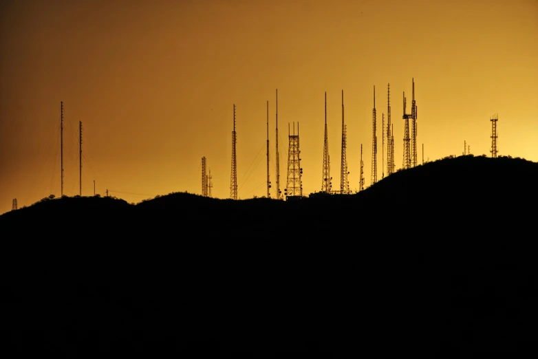 a group of cell towers sitting on top of a mountain, a portrait, flickr, backlit, tucson arizona, gold, spectrum