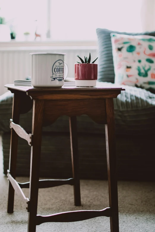 a small table with a laptop on top of it, pexels contest winner, arts and crafts movement, white mug, sitting in rural living room, shot on sony a 7, furniture