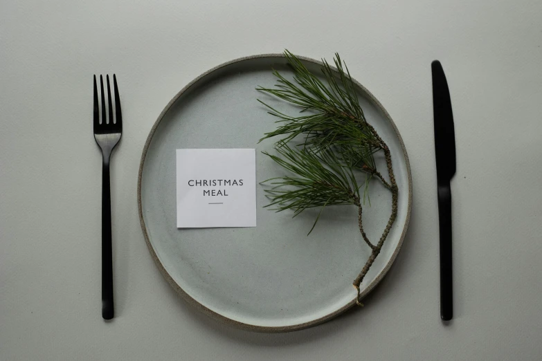 a white plate topped with a piece of paper next to a fork and knife, inspired by Ernest William Christmas, unsplash, label, grey, evergreen, bjarke ingels