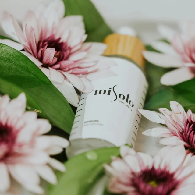 a close up of a bottle of lotion surrounded by flowers, by Lisa Milroy, unsplash, miko, product view, side shot, floro details