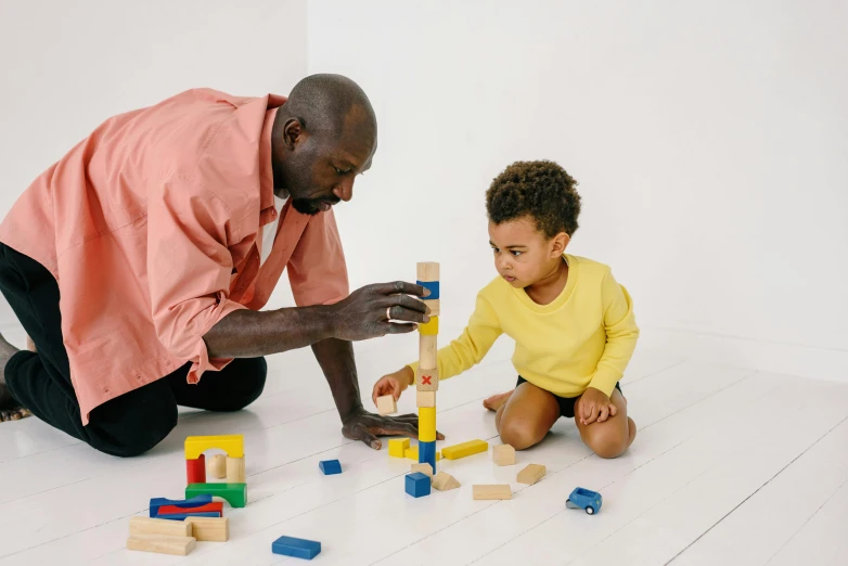 a man playing with a child on the floor, constructive solid geometry, profile image, black man, building blocks