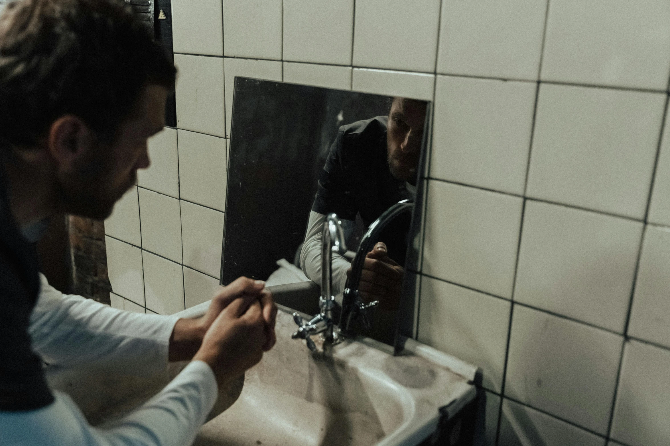 a man brushing his teeth in front of a mirror, by Elsa Bleda, hyperrealism, still from the movie saw, taps with running water, low quality photo, worksafe. cinematic