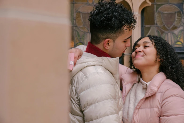 a man and a woman standing next to each other, pexels contest winner, renaissance, wearing a pink hoodie, leaning on door, latino features, couple kissing