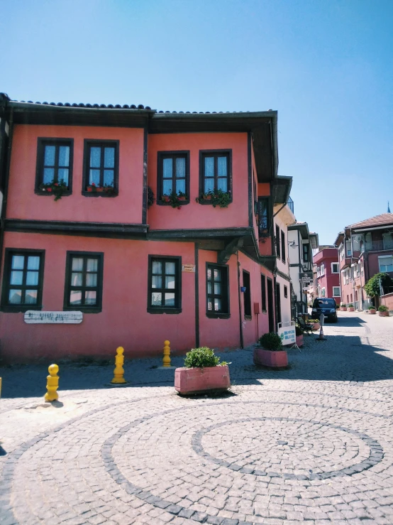 a pink building sitting on the side of a road, inspired by Niyazi Selimoglu, pexels contest winner, art nouveau, ottoman sultan, village square, 🚿🗝📝, front view 1 9 9 0