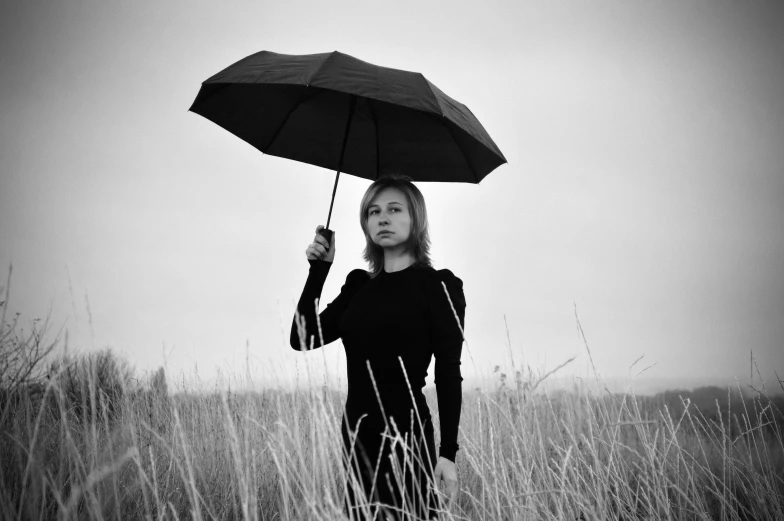 a woman standing in a field holding an umbrella, a black and white photo, by Stefan Gierowski, portrait image, sergey krasovskiy, hiroyuki kato, wearing black clothes