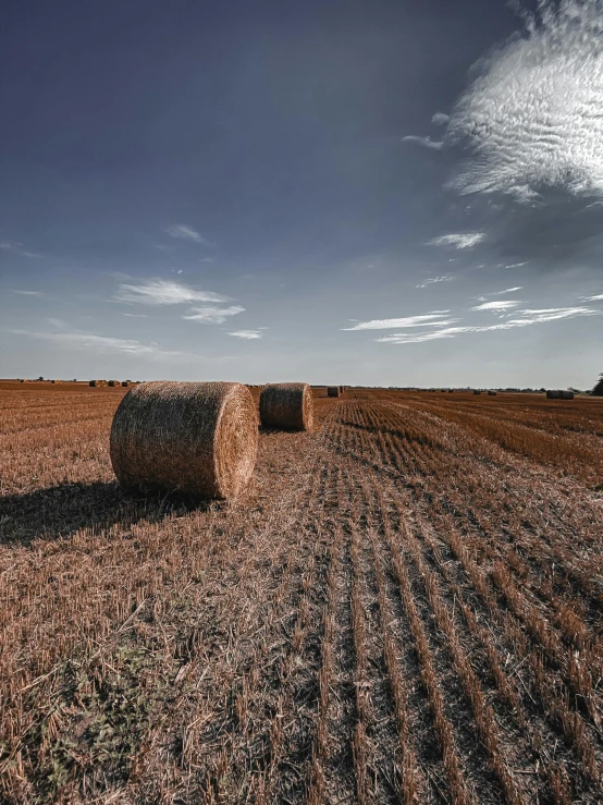 hay bales in a field under a cloudy sky, an album cover, pexels contest winner, land art, round format, hdri, high quality image