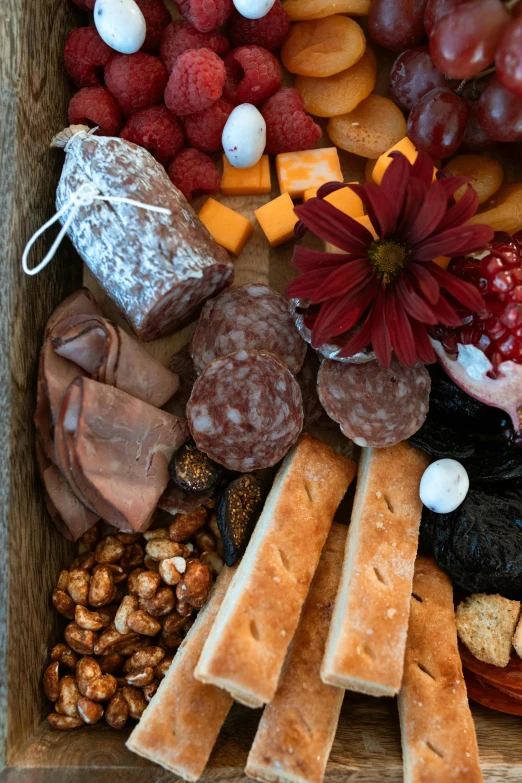 a wooden box filled with lots of different types of food, cheese and salami on the table, on center, up-close, prairie