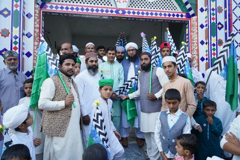 a group of people standing in front of a building, by Riza Abbasi, pexels contest winner, hurufiyya, holy ceremony, green and white, blue colored traditional wear, 2 5 6 x 2 5 6 pixels