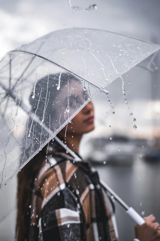 a woman holding an umbrella in the rain, pexels contest winner, standing next to water, headshot, hyperdetailed, instagram post