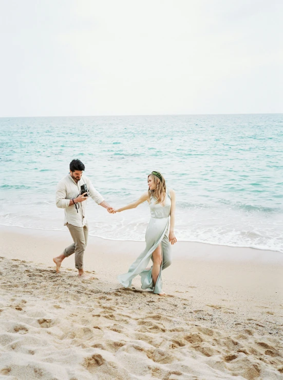 a man and a woman holding hands on a beach, by Arabella Rankin, pexels contest winner, renaissance, sea green color theme, 2 5 6 x 2 5 6 pixels, modest flowing gown, margot robbie on the beach